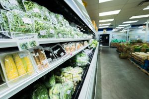 ShuangHurStore-36 Refrigerated produce shelf displaying packaged greens, corn, root vegetables, and leafy items labeled as kayang leaves.